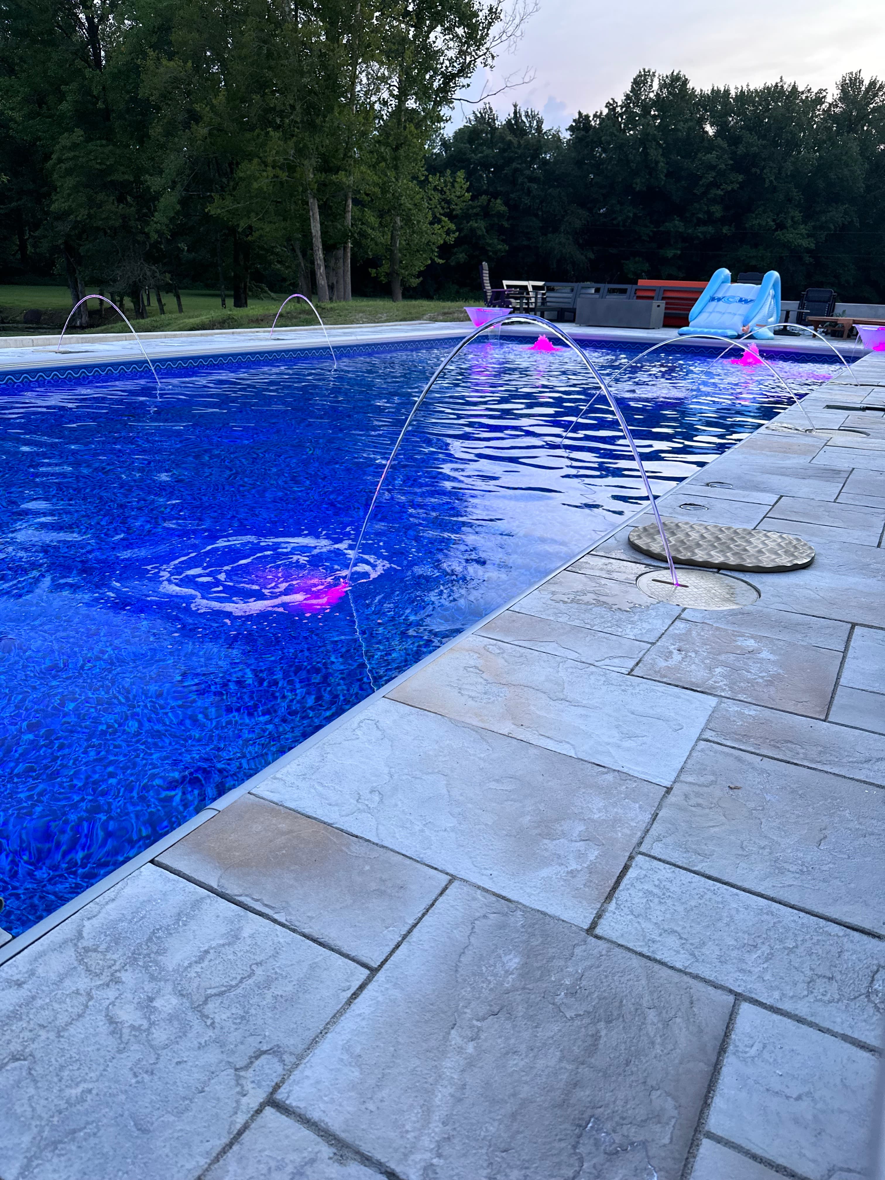 Custom inground pool with stone patio, water features, and LED lighting